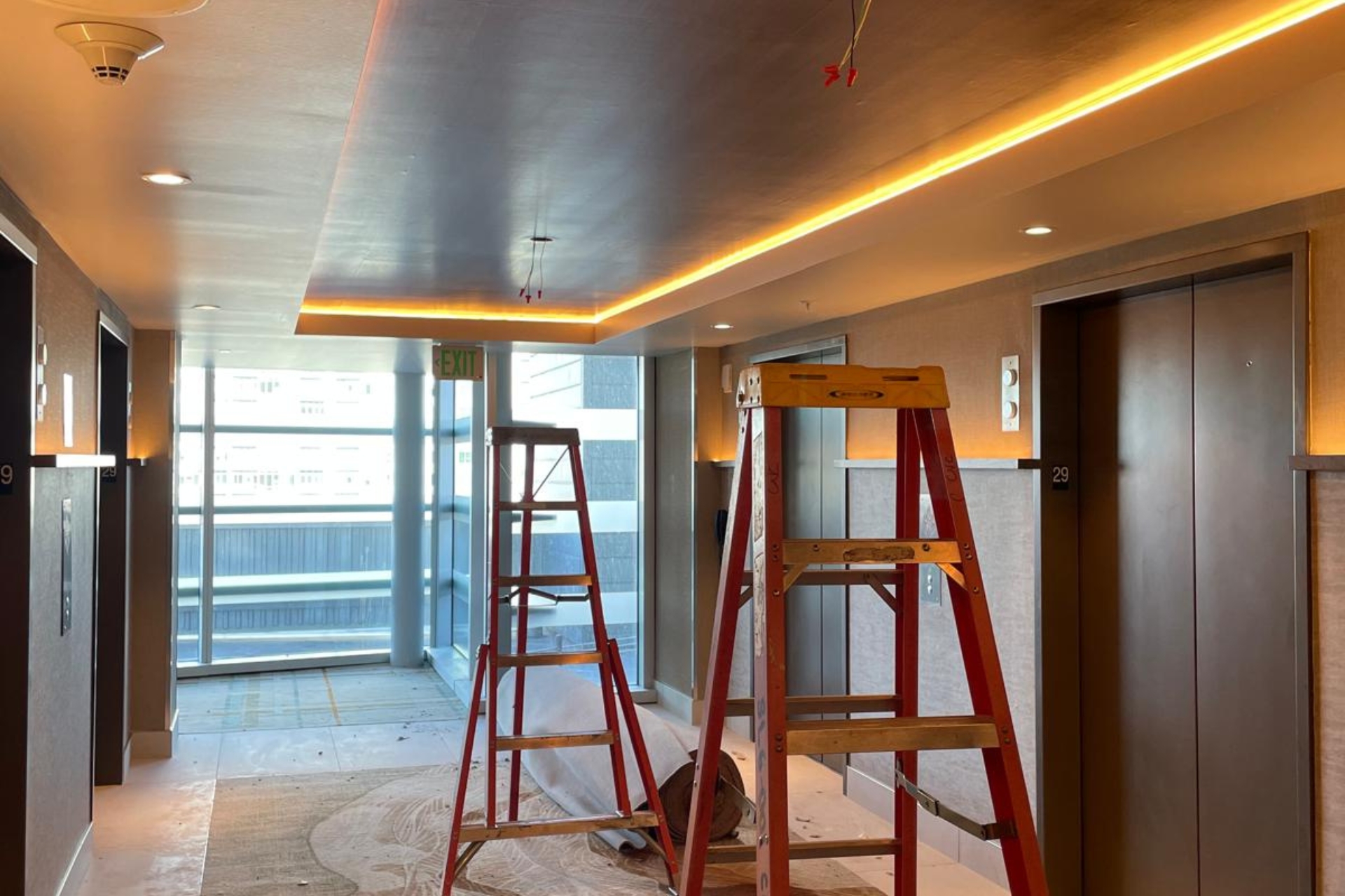 Interior hallway under renovation with ladders and construction materials.